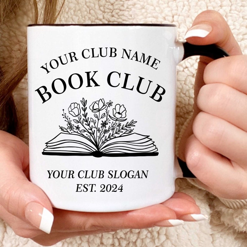 May include: White ceramic mug with a black rim and handle. The mug has a black and white design of an open book with flowers coming out of it. The text "YOUR CLUB NAME BOOK CLUB YOUR CLUB SLOGAN EST. 2024" is printed on the mug.