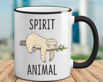 May include: White ceramic mug with a black rim and handle. The mug features a cartoon sloth hanging from a branch with the text "SPIRIT ANIMAL" printed on the mug.