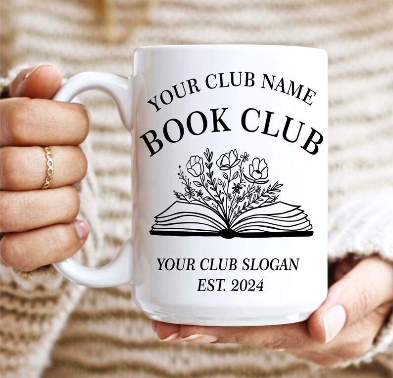 May include: White ceramic mug with a black design of an open book with flowers growing out of it. The text "YOUR CLUB NAME BOOK CLUB YOUR CLUB SLOGAN EST. 2024" is printed on the mug.