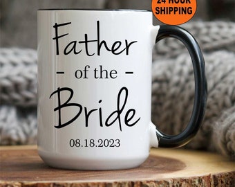 May include: White ceramic coffee mug with a black handle and black rim. The mug has the text "Father - of the - Bride" and the date "08.18.2023" printed on it.
