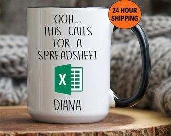 May include: White coffee mug with a black rim and handle. The mug has a black and white graphic of a spreadsheet with the text "Ooh... This calls for a spreadsheet" and "Diana".