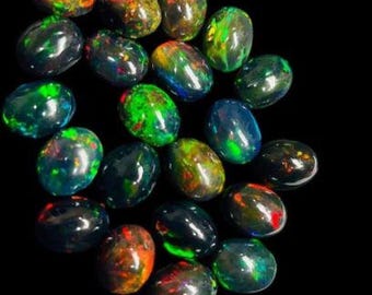 Puede incluir: Un conjunto de ópalos negros ovalados, cada uno mostrando juegos de color. Los ópalos exhiben una gama de colores, incluyendo verde, rojo, azul y amarillo, sobre un fondo oscuro. Las piedras preciosas están pulidas y tienen un aspecto brillante.