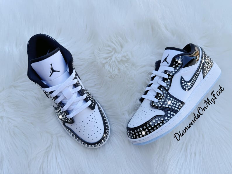 May include: Pair of white and black sneakers with crystal embellishments. The shoes feature a black Nike swoosh and the Jumpman logo. The text "DiamondsOnMyFeet" is visible on the right shoe.