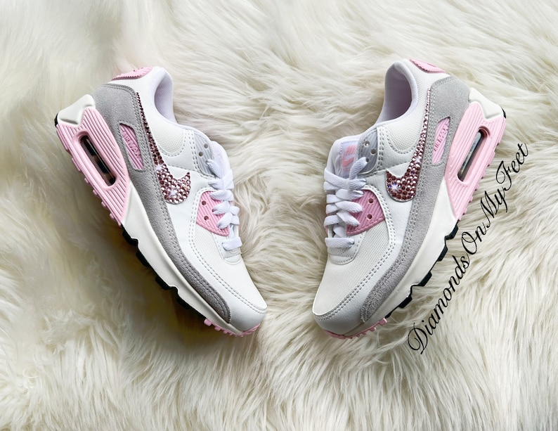 May include: White and grey Nike Air Max 90 sneakers with pink accents and rhinestones on the swoosh logo. The text "Diamonds On My Feet" is visible on the right shoe.