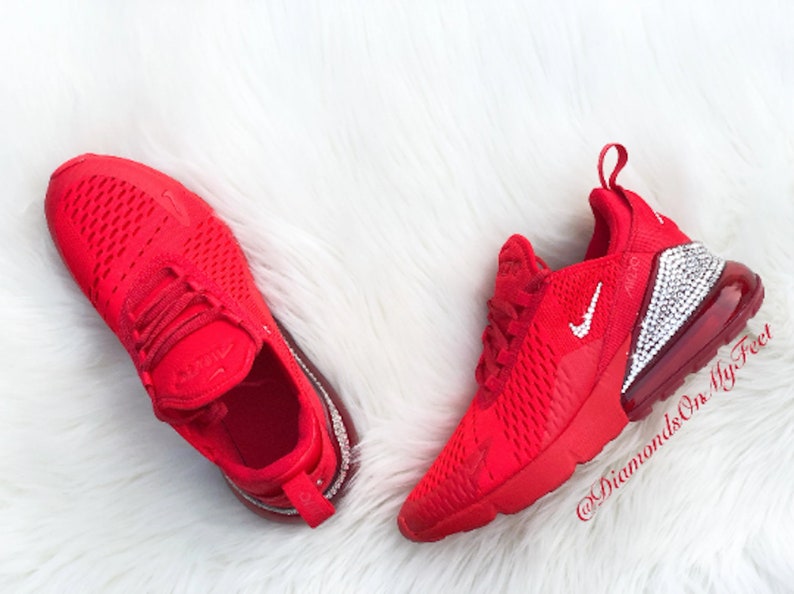 May include: Red Nike Air Max 270 sneakers with a white swoosh and a crystal-encrusted heel. The shoes are on a white fluffy surface. @DiamondsOnMyFeet