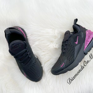 May include: Black Nike Air Max 270 sneakers with pink rhinestones on the back and side. The shoes are on a white fluffy surface. "Diamonds On My Feet" is written in the bottom right corner.