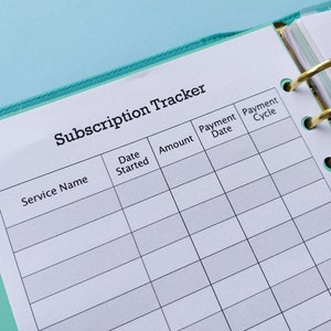 May include: A white page with a teal binder, titled "Subscription Tracker". The page is divided into columns with headings: "Service Name", "Date Started", "Amount", "Payment Date", and "Payment Cycle".