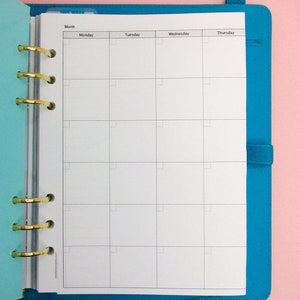 May include: A white weekly planner with a blue cover. The planner has a tab for each day of the week: Monday, Tuesday, Wednesday, and Thursday. The planner is open to the week of the month.