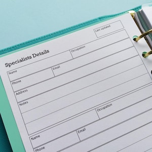 May include: A white page with a black border and the text "Specialists Details" at the top. The page is divided into sections for name, phone, address, email, occupation, and notes. The page is from a bound notebook with gold rings.