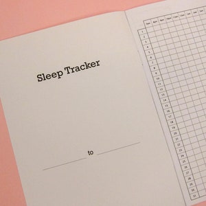 Pu&ograve; includere: Un quaderno bianco con le parole "Sleep Tracker" stampate sulla copertina. Il quaderno ha una pagina a griglia per tenere traccia dei modelli di sonno.