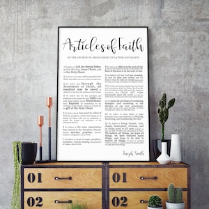 May include: A black and white printable poster with the text "Articles of Faith" and the 13 articles of faith of the Church of Jesus Christ of Latter-day Saints. The poster is framed and hanging on a wooden dresser with numbered drawers.