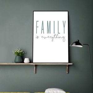 May include: A framed print with the text "FAMILY is everything" hanging on a wall above a yellow couch and a wooden shelf with a vase of white flowers and a white ceramic object.