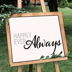 May include: A wooden easel displaying a sign with the words "Happily Ever Always" in black script. The sign is framed in wood and decorated with green foliage. The background is a grassy area.