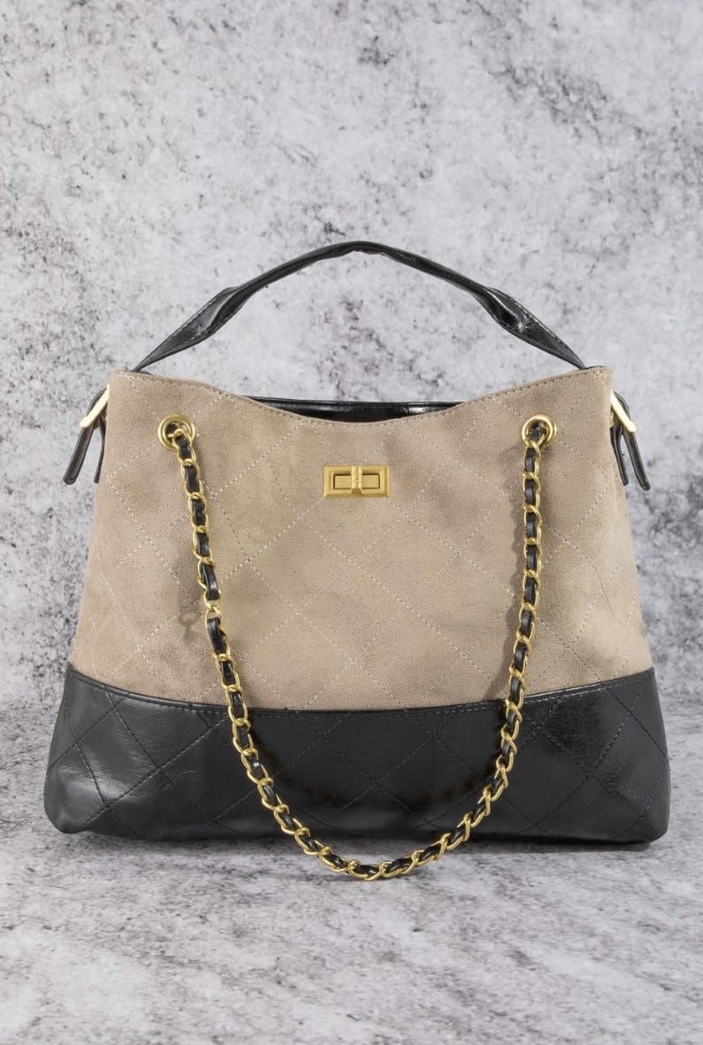 Pode incluir: Bolsa bege e preta com al&ccedil;a de corrente dourada. A bolsa tem uma parte superior de camur&ccedil;a bege acolchoada e uma parte inferior de couro preto. A al&ccedil;a &eacute; preta e a bolsa tem um fecho dourado.