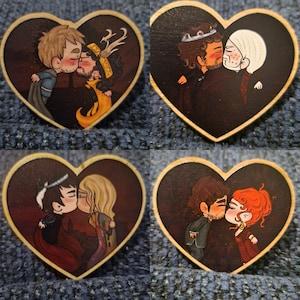 以下が含まれることがあります： それぞれキスをしている漫画のカップルを描いた、4つのハート型の木製オーナメント。カップルはさまざまな髪の色と服装をしています。背景は暗く、縁は天然木の色です。装飾品。