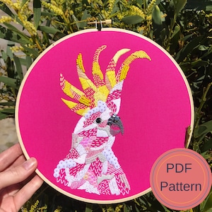 May include: Embroidered hoop art featuring a pink and yellow cockatoo on a bright pink background. The text "PDF Pattern" is visible in the lower right corner.