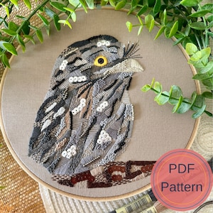 May include: Embroidered owl with brown, grey, and white thread on a beige fabric background. The owl is surrounded by a wooden embroidery hoop. The text "PDF Pattern" is in a red circle in the lower right corner of the image.