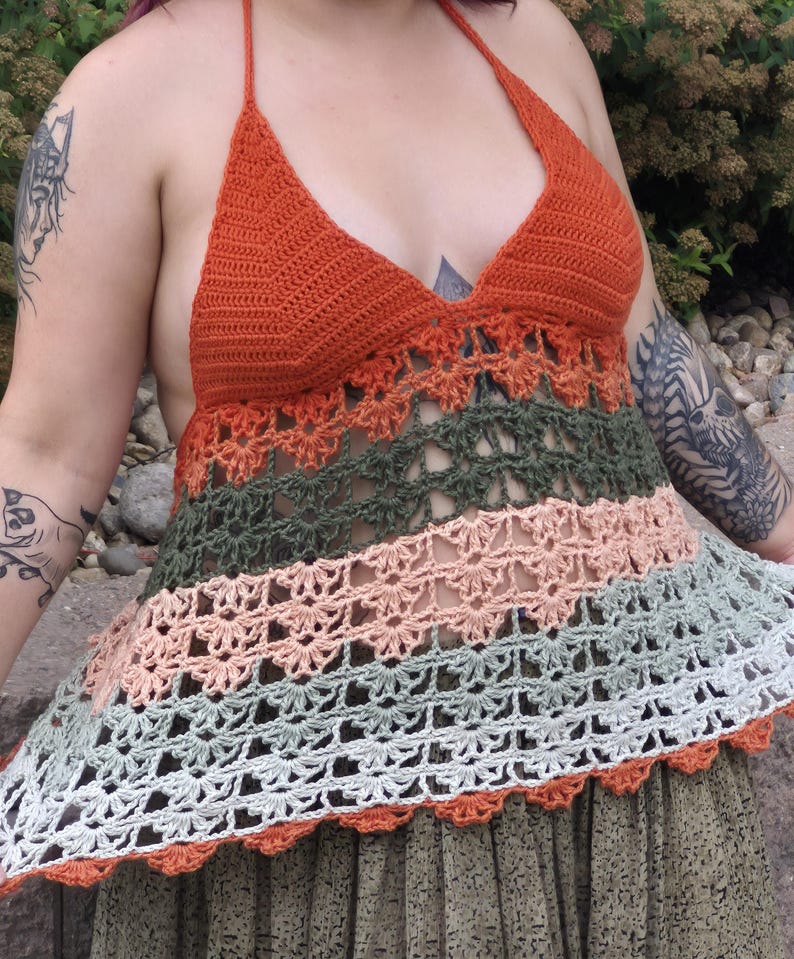 May include: A handmade crochet halter top in shades of orange, green, peach, and white. The top features a halter neck and a flared, openwork design. The bottom edge has a scalloped trim.