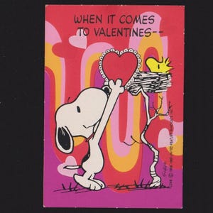 May include: A vintage Valentine's Day card featuring Snoopy holding a heart with Woodstock in a nest. The card has a red background with the text "WHEN IT COMES TO VALENTINES--" and a retro design in pink, orange, and yellow.
