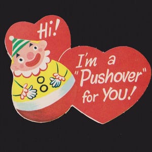 May include: A vintage Valentine's Day card featuring a cartoon clown figure and two red heart shapes. The hearts contain the phrases "Hi!" and "I'm a 'Pushover' for YOU!" The card is approximately 3 inches in height.