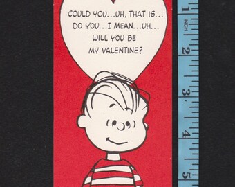 May include: A vintage Valentine's Day card featuring a cartoon boy with a heart-shaped thought bubble. The red card has the text "COULD YOU...UH, THAT IS...DO YOU...I MEAN...UH...WILL YOU BE MY VALENTINE?" The card is approximately 4 inches tall.