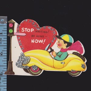 May include: Vintage Valentine's Day card featuring a yellow car driven by a young person wearing a cap and scarf. The card has a red heart with the text "STOP WAITING! BE MINE - NOW!" and glitter accents. A traffic light is on the left.