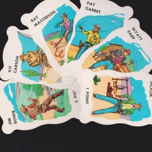 May include: A vintage card game featuring illustrations of cowboys and the names Bat Masterson, Kit Carson, Jim Bowie, Pat Garret, Wyatt Earp, and Wild Bill Hickok. The cards have a white border and are arranged in a circular pattern.