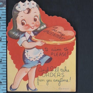 May include: Vintage Valentine's Day card featuring a cartoon waitress in a blue dress and apron, holding a heart-shaped cake. The card has text that reads "To my Valentine," "I aim to please!" and "And I'll take orders from you anytime!"