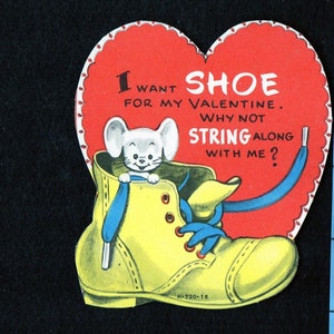 May include: A vintage Valentine's Day card in the shape of a red heart with a scalloped edge. The card features a yellow boot with blue laces and a cartoon mouse. Text on the card reads, "I want shoe for my Valentine. Why not string along with me?"