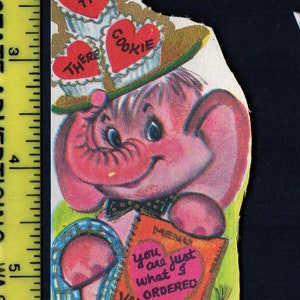 May include: Vintage Valentine's Day card featuring a pink elephant with a hat and a menu. The menu reads "You are just what I ordered Valentine." The card has a gold and green color scheme.