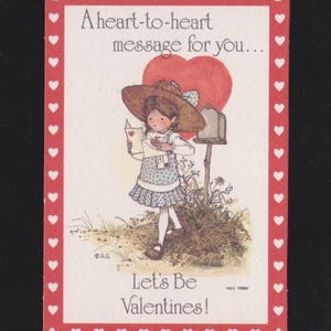 May include: A vintage Valentine's Day card with a red border adorned with white hearts. The card features a girl in a dress and hat reading a letter in front of a mailbox and a large heart. Text reads: "A heart-to-heart message for you... Let's Be Valentines!"
