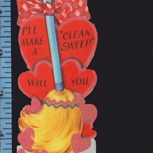 May include: A vintage-style Valentine's Day card featuring a broom with a yellow bristle head and a blue handle, topped with a red and white checkered bow. Red hearts surround the broom with the text "I'LL MAKE A CLEAN SWEEP WILL YOU Be My Valentine". A ruler shows the card is 6 inches tall.