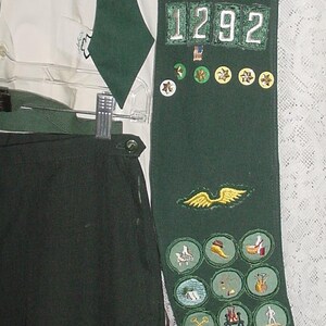 May include: A dark green sash with the text "NORTHWEST GEORGIA" and the number "1292" is displayed. The sash is adorned with various patches and badges, along with a white shirt and dark green pants.