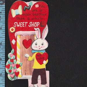 May include: Vintage Valentine's Day card featuring a cartoon rabbit holding a heart that says "My Love." The card has a red heart-shaped top with the text "You are a nicer teacher than a whole SWEET SHOP."