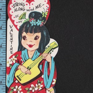 May include: Vintage Valentine's Day card featuring a cartoon girl in a red kimono with white floral accents, playing a yellow ukulele. The card has a heart-shaped top with the text "String along with me - Be my Valentine."