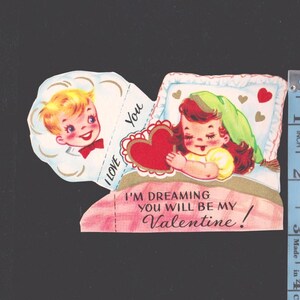 May include: Vintage Valentine's Day card featuring a boy and a girl. The girl is in bed holding a heart, with the text "I'm dreaming you will be my Valentine!". The boy has a bow tie and the text "I love you".