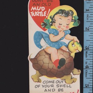 May include: Vintage Valentine's Day card featuring a cartoon girl riding a turtle. The girl wears a blue dress and yellow hat. Text includes "Don't be an old mud turtle!" and "Come out of your shell and be my Valentine!"
