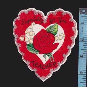 May include: A heart-shaped greeting card with a red border and a white heart in the center. The card features a red rose, lily of the valley, and the text "Especially for You Teacher". The card measures approximately 4 inches in height.