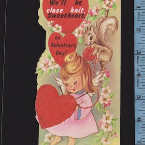 May include: Vintage Valentine's Day card featuring a cherubic angel in a pink dress holding a red heart. A squirrel knits yarn near a floral branch. The card reads "We'll be close knit, Sweetheart, on Valentine's Day!" Made in USA.