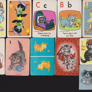 May include: A selection of vintage playing cards with cartoon cat illustrations. The cards show various cat images, including kittens with yarn, cats playing with balls, and cats wearing hats. Some cards have text such as "Pretty Kitty" and "Meow-Meow".