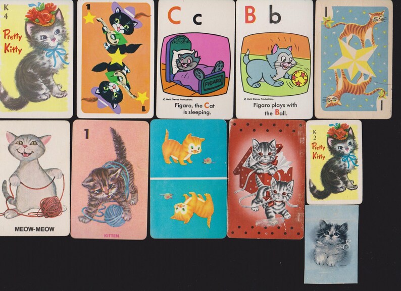 May include: A selection of vintage playing cards with cartoon cat illustrations. The cards show various cat images, including kittens with yarn, cats playing with balls, and cats wearing hats. Some cards have text such as "Pretty Kitty" and "Meow-Meow".