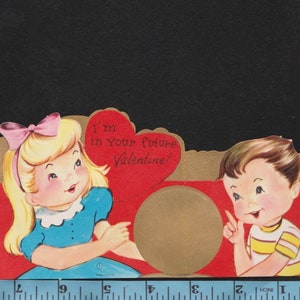 May include: Vintage Valentine's Day card featuring a cartoon boy and girl. The girl wears a blue dress and pink bow, the boy a yellow striped shirt. A red heart with the text "I'm in Your future Valentine!" is in the center.