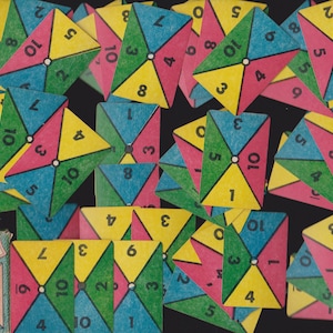 May include: A collection of colorful Cross Numbers Game cards. Each card features a geometric design with four triangles in yellow, pink, blue, and green, with numbers from 1 to 10. A small card with the game's title is also visible.
