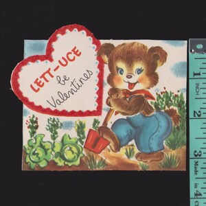 May include: Vintage Valentine's Day card featuring a cartoon bear in blue overalls and a red scarf, holding a shovel. The card includes a heart-shaped message that reads "LETT-UCE be Valentines". The card is approximately 3 inches in height.