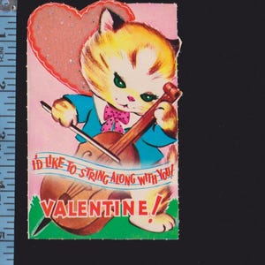 May include: Vintage Valentine's Day card featuring a cartoon cat playing a violin. The cat wears a blue jacket and pink bow tie. The card has a pink heart and the text "I'd like to string along with you! Valentine!"