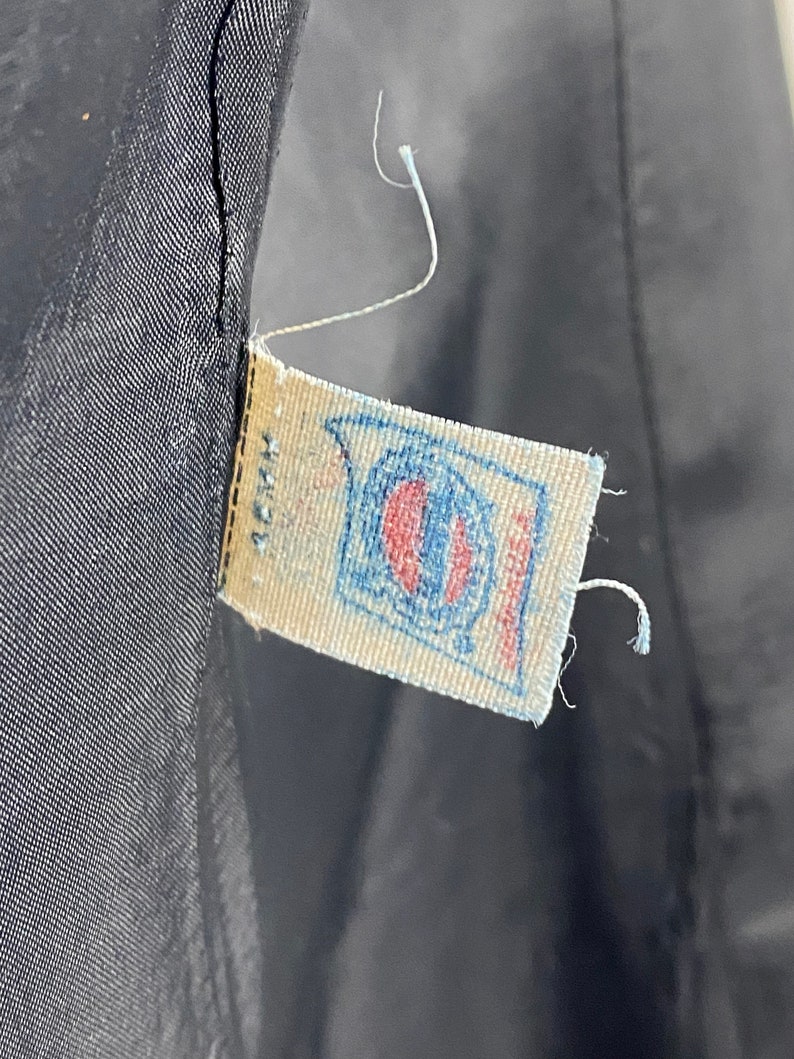 May include: A close-up of a white fabric label with blue and red stitching. The label has a blue circle with a white center and the text "Made in USA" printed on it.