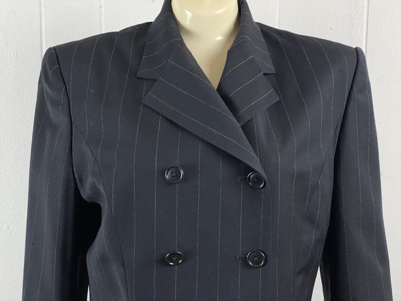 May include: A black pinstripe blazer with a double-breasted closure and four buttons.
