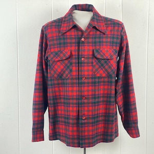 May include: Red and green plaid long-sleeve shirt with two chest pockets. The shirt has a button-down front and a classic collar. The plaid pattern is a mix of red, green, and black.