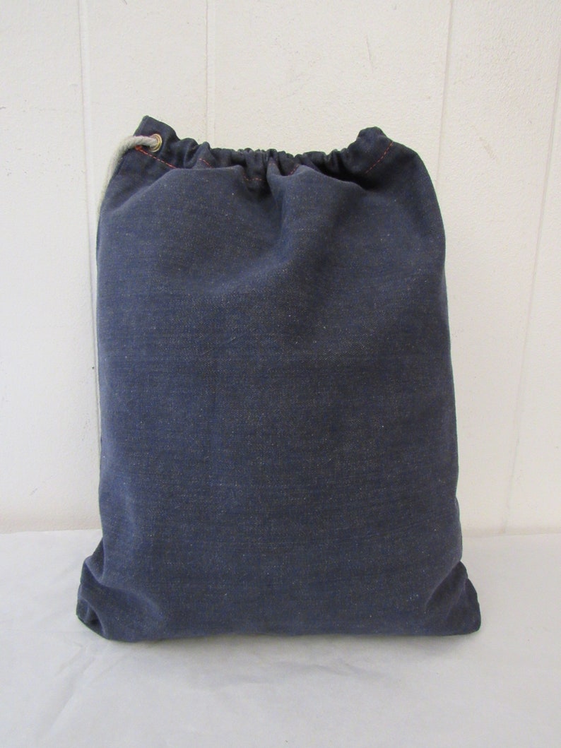 K&ouml;nnte beinhalten: Eine dunkelblaue Kordeltasche aus Canvas mit einem wei&szlig;en Kordelzug.