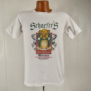 May include: White t-shirt with a graphic of a beer stein and the text "Schaefer's Munchen Deutschland".